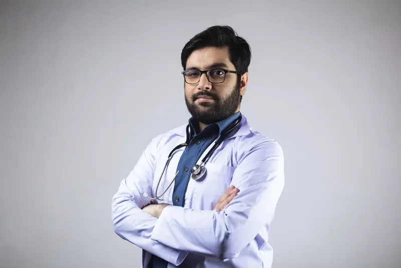A doctor in a white coat with a stethoscope, arms folded