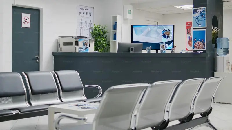 A clinic reception desk with the patient waiting area behind it